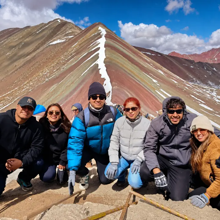 Six travelers posing before Rainbow Mountain in Peru.