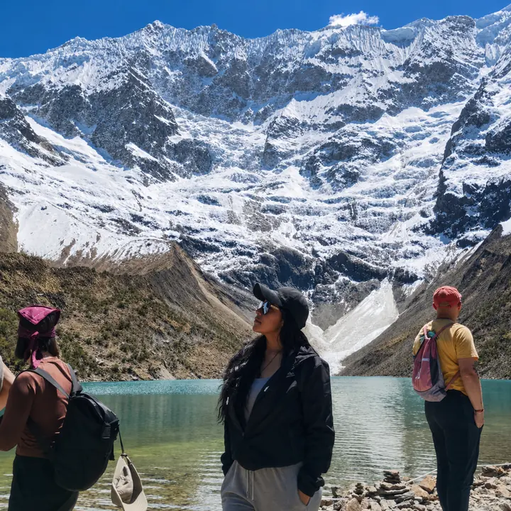 Woman admiring Humantay Lake and the surrounding snow-covered peaks.