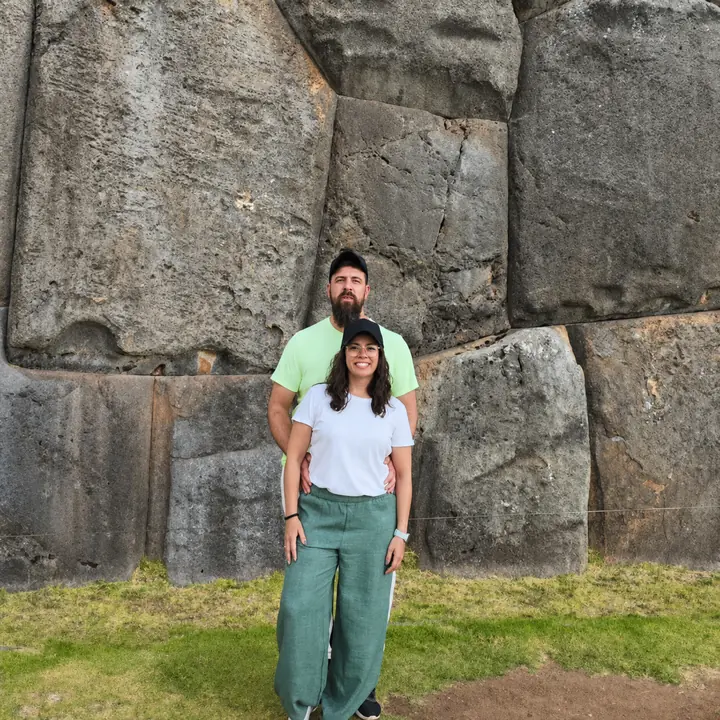Couple posing beside the massive Inca stone walls of Sacsayhuaman in Cusco.