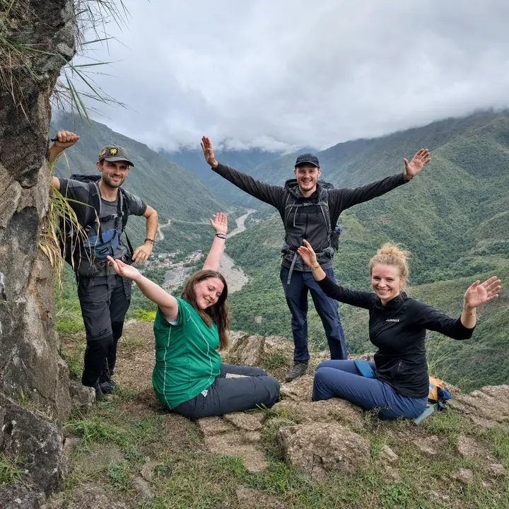 Four hikers celebrating above a misty valley on the Inca Jungle trail.