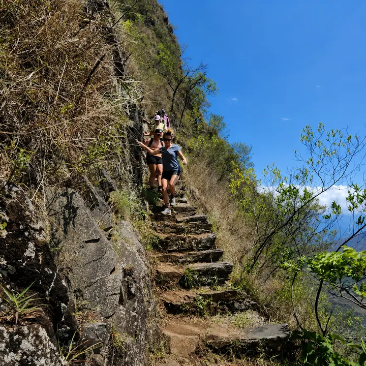 Hikers descending a steep mountain trail during the Inca Jungle trek.