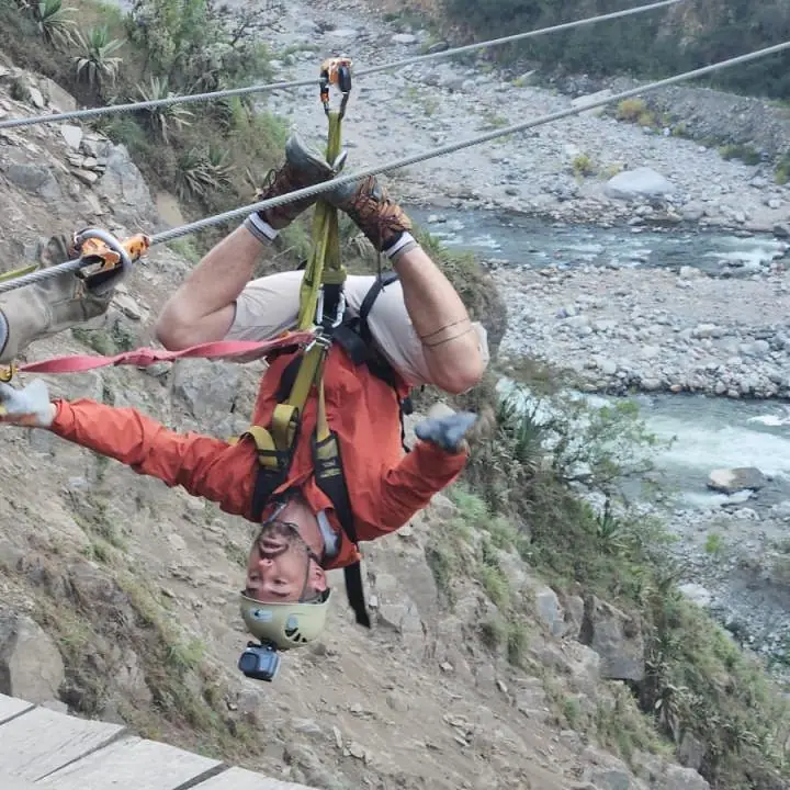 Traveler ziplining above a river valley during the Inca Jungle adventure.