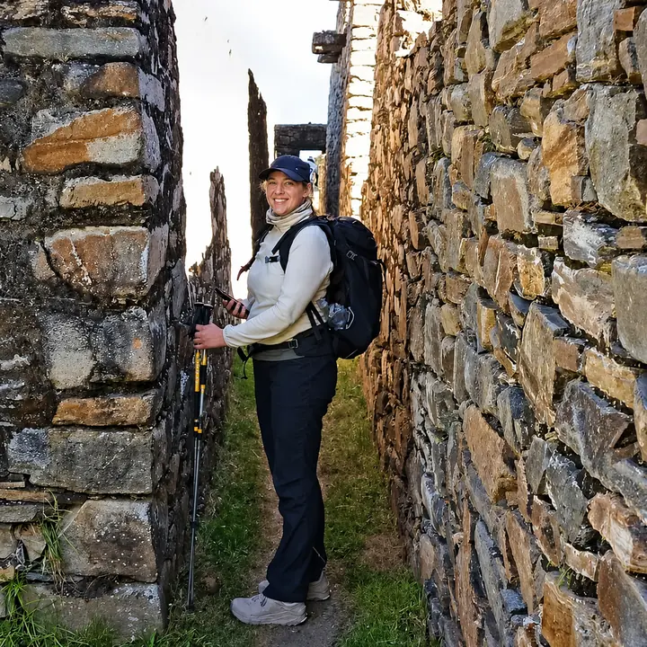 Traveler walking through a narrow stone corridor in the Choquequirao ruins.